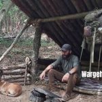 Wargeh Bushcraft with his dog Agir resting inside his wooden log cabin