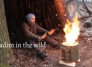 Vadim in the wild happily sitting near swedish fire torch in the forest of Ukraine.